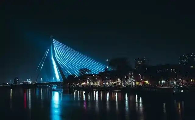 Verlichte Erasmusbrug in Rotterdam, schitterend weerspiegeld in het water van de Maas.
