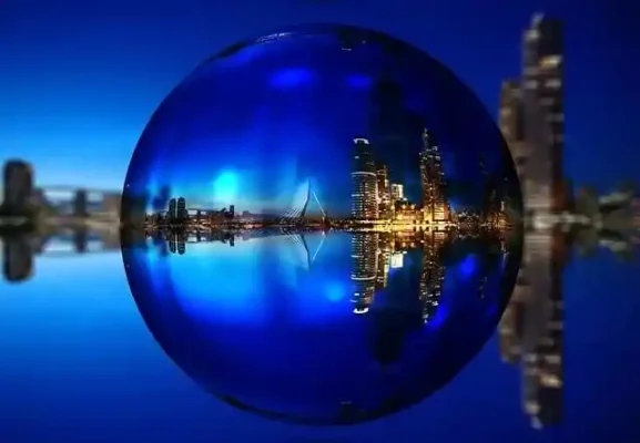 Nachtfoto van de Erasmusbrug en de Wilhelminapier in Rotterdam, gezien door een glazen bol, met de stad prachtig weerspiegeld.